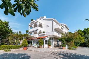 a large white building with plants and trees at Apartments with a parking space Banjol, Rab - 5022 in Rab