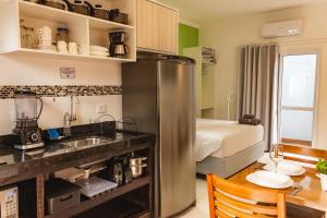 a kitchen with a stainless steel refrigerator and a bedroom at Solarium Flats Itagua - Ubatuba SP in Ubatuba