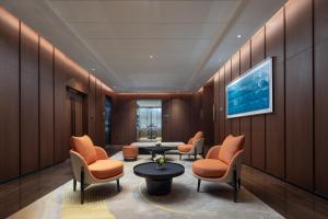 - une salle d'attente avec des chaises orange et une table dans l'établissement Hilton by Hampton Guangzhou Xintang, à Zengcheng