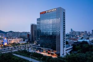 a tall building with a sign on it in a city at Hilton by Hampton Guangzhou Xintang in Zengcheng