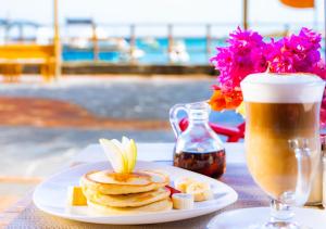 a plate of pancakes and a cup of coffee and flowers at La Zayapa Hotel in Puerto Baquerizo Moreno