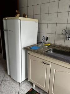 a kitchen with a white refrigerator and a sink at Apto Espaçoso no Centro de Ubatuba - 3 quartos, 2 vaga garagem,2 banheiros,Cozinha Completa in Ubatuba