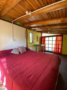 Una gran cama roja en una habitación con techo de madera. en Casa Sol y Luna, en Villa General Belgrano