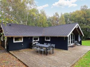 a house with a table and chairs on a deck at Four-Bedroom Holiday home in Væggerløse 8 in Marielyst