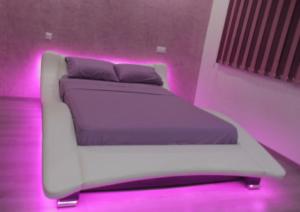- une chambre avec un lit blanc et des lumières roses dans l'établissement Rabat Apartments, à Rabat