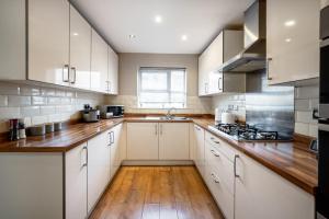a kitchen with white cabinets and a wooden floor at Manchester Serviced Accomodation NorthernNightzzz - The Gardens in Manchester