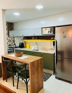 a kitchen with a table and a stainless steel refrigerator at Apartamento na Praia de Palmas com garagem in Governador Celso Ramos