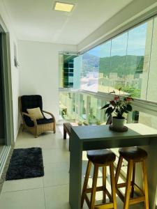 a living room with a table and chairs and a large window at Apartamento na Praia de Palmas com garagem in Governador Celso Ramos