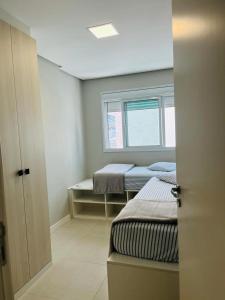a small room with two beds and a window at Apartamento na Praia de Palmas com garagem in Governador Celso Ramos