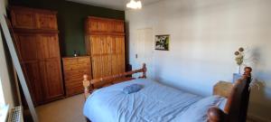 1 dormitorio con 1 cama con sábanas azules y armarios de madera en Victorian Semi Detached House behind the High Street, en Newton in Makerfield