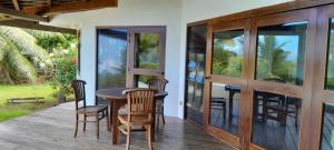 una terraza de madera con mesa y sillas de madera en CHEZ TAUA maison isolée pas de wifi ni bus en Opoa