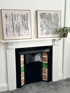 a fireplace with two pictures on top of it at Longsands Apartment, Tynemouth Luxury Coastal Retreat in Tynemouth