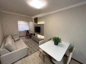 ein Wohnzimmer mit einem weißen Tisch und einem weißen Sofa in der Unterkunft Apto super luxo beira mar Capão da Canoa in Capão da Canoa