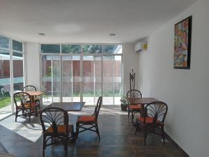 a dining room with tables and chairs and windows at Villas Carlota Cancún in Cancún