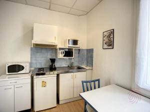 małą kuchnię z białymi urządzeniami i stołem w obiekcie Studio cosy proche des Thermes, centre-ville et nature, WiFi, animaux acceptés - FR-1-451-181 w mieście Lamalou-les-Bains +12 zdjęć