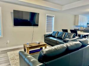 a living room with black leather furniture and a flat screen tv at Just 5 Minuts drive from Cobourg Beach in Cobourg