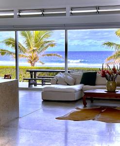 Coast Cook Islands في راروتونغا: غرفة معيشة مع أريكة بيضاء وإطلالة على المحيط