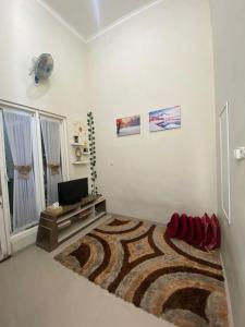 een witte kamer met een televisie en een tapijt bij Villa Aslam Kayana Batu in Karangploso