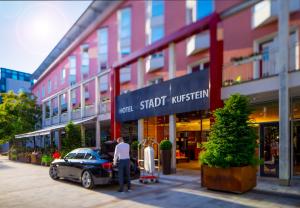 a man standing next to a car in front of a building at Hotel Stadt Kufstein in Kufstein