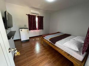 Dormitorio pequeño con cama y nevera en S&P Huayau Resort น้ำอ้อย, en Ban Huai Ya-u