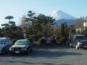 dois carros estacionados num parque de estacionamento em frente a uma montanha em Fujimien em Fujikawaguchiko