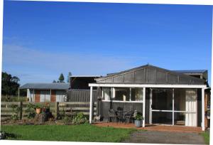 une maison avec une terrasse couverte et une clôture dans l'établissement Fig Tree Cottage, à Greytown