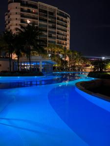 a swimming pool at night with a building in the background at Santa Mônica Barra in Rio de Janeiro