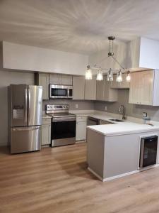 una cocina con electrodomésticos de acero inoxidable y armarios blancos en Newly renovated -2 Bedroom Condo, en Boston