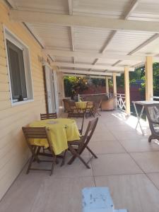 un patio con una mesa amarilla y sillas. en Lacréola en Saint-Joseph