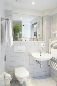 a white bathroom with a toilet and a sink at Bischofshol in Hannover