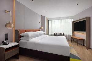 a bedroom with a large white bed and a television at Home2 Suites by Hilton Beijing West Station in Beijing