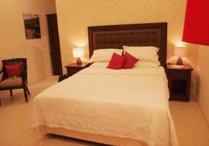 um quarto com uma grande cama branca com almofadas vermelhas em The Gecho Inn Country em Jepara