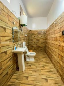 a bathroom with a toilet and a sink and wooden walls at Camp Banas Naudhiya in Budia