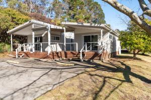 a small white house with a large porch at Blackheath Glen Tourist Park in Blackheath