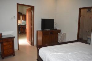 Dormitorio con cama y tocador con TV en The Gecho Inn Country en Jepara