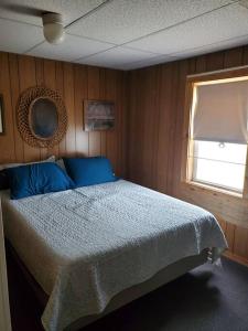 Un dormitorio con una cama con almohadas azules y una ventana en Tranquil 4br lakefront home with wrap around deck, en Warner
