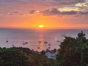 un tramonto sull'oceano con barche in acqua di Bungalow Jamaïque a Deshaies
