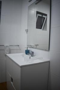 La salle de bains blanche est pourvue d'un lavabo et d'un miroir. dans l'établissement Bella's Hideaway, à Ponta Delgada