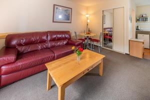 - un salon avec un canapé en cuir rouge et une table basse dans l'établissement Daffodil Motel, à Christchurch