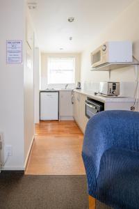 Il comprend une cuisine équipée d'appareils électroménagers blancs et d'une chaise bleue. dans l'établissement Daffodil Motel, à Christchurch