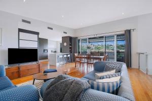 a living room with a couch and a tv at Top of Taringa Penthouse with Sweeping Views in Brisbane