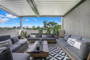 uma sala de estar com sofás e uma mesa em Top of Taringa Penthouse with Sweeping Views em Brisbane