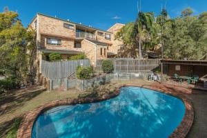 una piscina di fronte a una casa di The Hidden Flower - A Spacious Poolside Abode a Brisbane