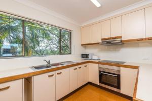 una cucina con armadietti bianchi e una finestra di The Hidden Flower - A Spacious Poolside Abode a Brisbane