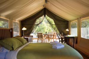 a bedroom with a bed in a tent with a table at Tanja Lagoon Camp in Tanja