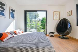 a bedroom with a bed and a chair in front of a window at Villa Notre-Dame - Piscine parking 4 chambres in Marseille