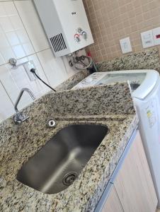 a kitchen counter with a sink and a washing machine at Apartamento Beira mar Capão da Canoa in Capão da Canoa