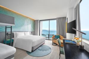 a hotel room with a bed and a large window at voco Ma Belle Danang, an IHG Hotel in Da Nang