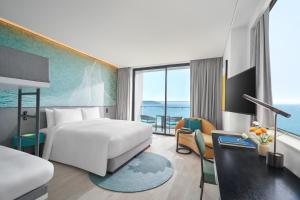 a hotel room with a bed and a large window at voco Ma Belle Danang by IHG in Da Nang
