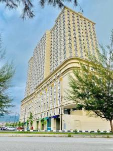 un gran edificio alto con un árbol delante en Champs Elysees Homestay by Landmark @ Kampar en Kampar